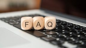 Three wooden cubes with the letters F, A and Q lie on a laptop keyboard.