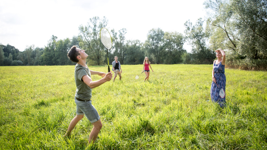 Students playing badminton in a park.